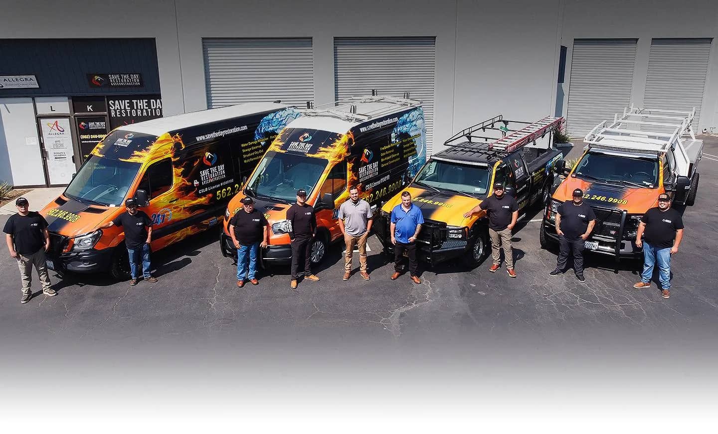 Save The Day Restoration staff standing beside the company’s orange service vehicles